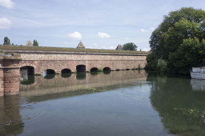 Reflection of built structure in river against sky