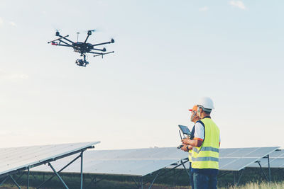 Low angle view of man using mobile phone against sky