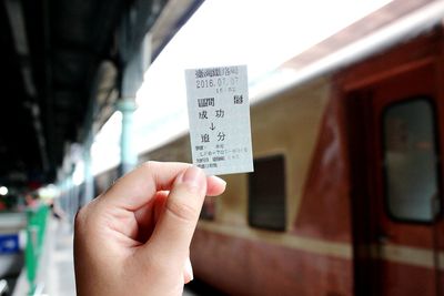Cropped hand of person holding ticket at railroad station platform