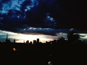 Silhouette of city against sky at dusk
