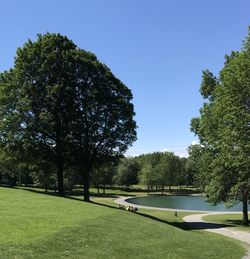 Scenic view of golf course against clear blue sky