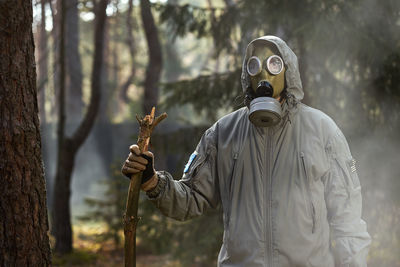 Person wearing mask against trees in forest