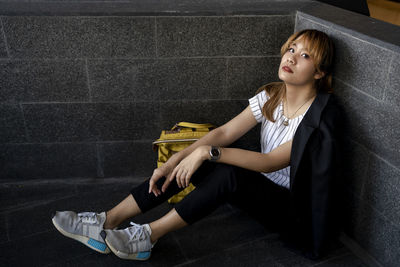 Portrait of businesswoman sitting by wall