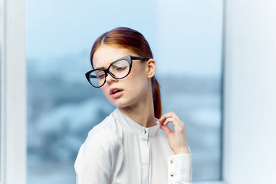 Portrait of young woman standing against window