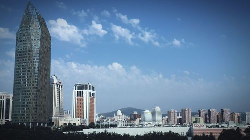 Low angle view of modern buildings against cloudy sky