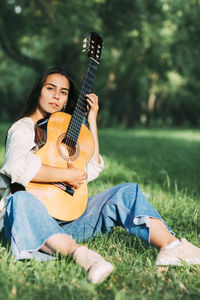 An attractive girl with a guitar in the park. the concept of creative hobbies and professionals.