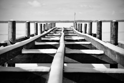 Wooden posts on pier over sea against sky