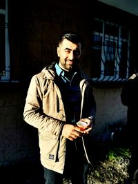 Portrait of smiling man standing against house