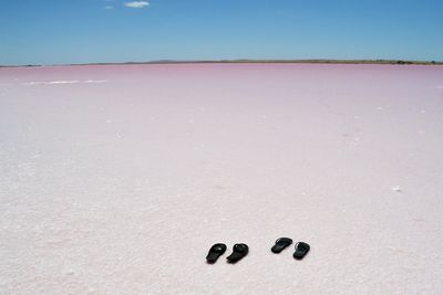 Footprints on sand at beach against clear sky