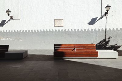 Empty bench against building wall