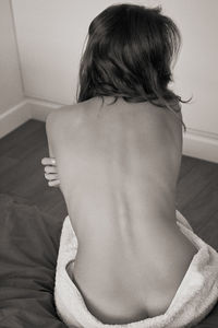 Rear view of woman sitting on bed