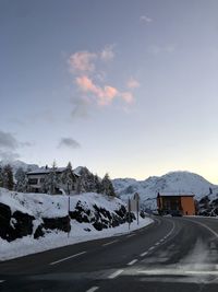 Snow covered road by mountain against sky