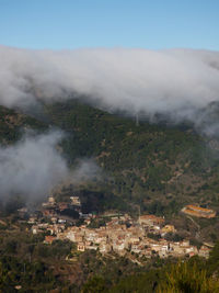 Smoke emitting from mountain against sky