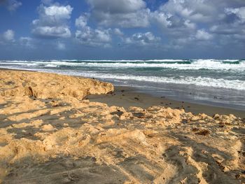 Scenic view of beach against cloudy sky