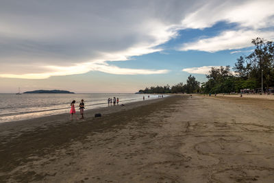 People on beach against sky during sunset