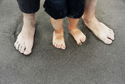 Low section of father and child standing at beach