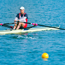 Young man rowing on sea