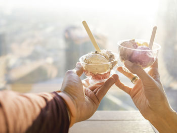 Man and woman hold ice-cream. cold dessert.  gelato with wooden spoons. romantic date in cafe.