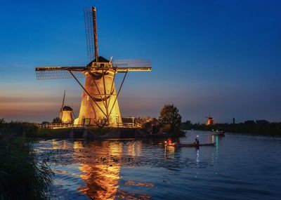 Traditional windmill by river against sky