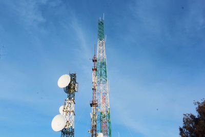 Low angle view of communications tower against blue sky