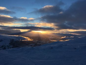 Scenic view of landscape against dramatic sky during sunset