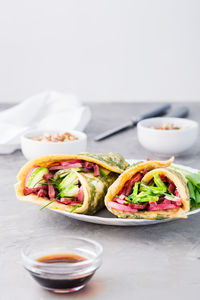 Egg rolls filled with pastrami, vegetables and green onions on a plate, sprouted grains