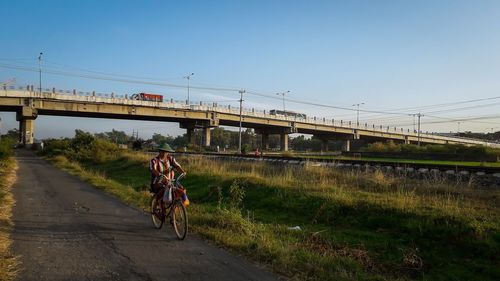 Man riding bicycle on road against sky