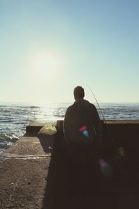 Rear view of man standing at beach against clear sky