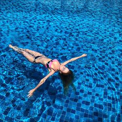 High angle view of woman in bikini floating on water in swimming pool