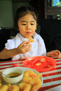 Cute girl eating food at home