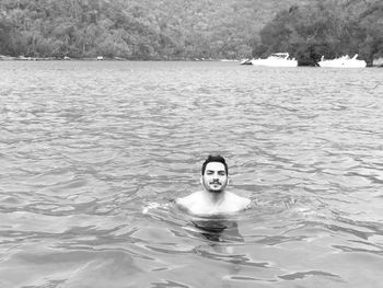 Portrait of shirtless young man swimming in lake