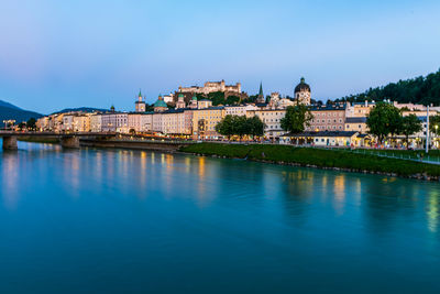 View of river and buildings against blue sky