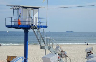 Lookout tower and people at beach against sky