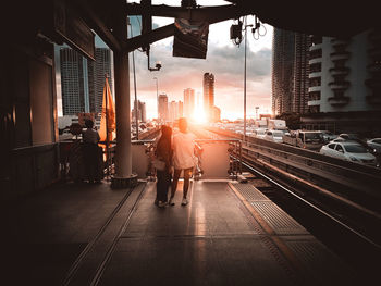 Rear view of people on street in city at sunset