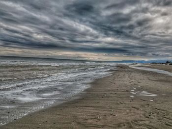 Scenic view of beach against cloudy sky