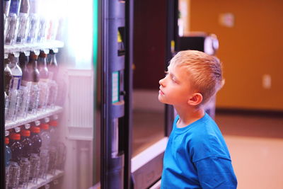 Boy standing and looking at vending machine in store