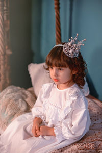 Portrait of girl sitting on bed at home