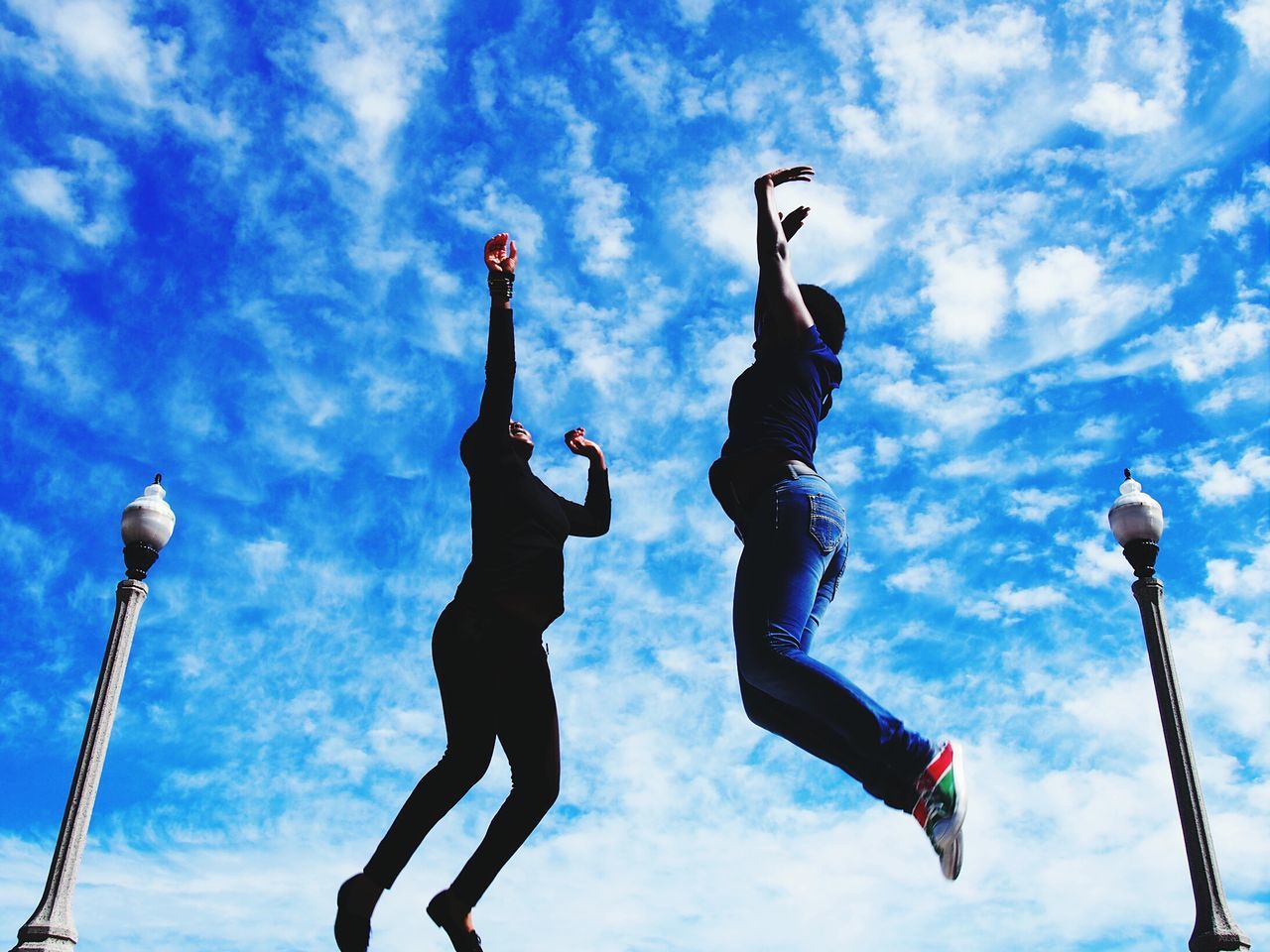 low angle view, sky, cloud - sky, human representation, sculpture, blue, cloudy, cloud, statue, art and craft, flag, day, outdoors, art, pole, street light, creativity, patriotism, hanging