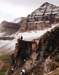 Man on rock by mountain against sky