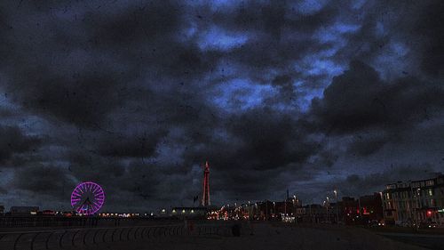 Low angle view of illuminated ferris wheel in city at night