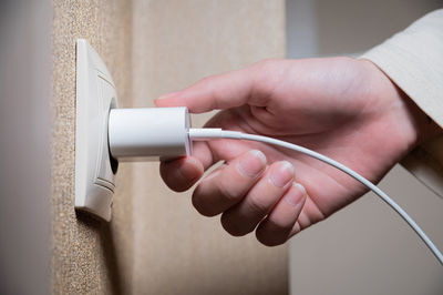 Hand of woman plugging adapter in electrical outlet