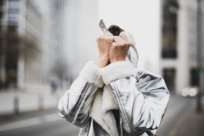 Woman covering face with hands in city