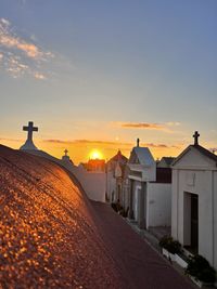 Rear view of woman walking on field against sky during sunset