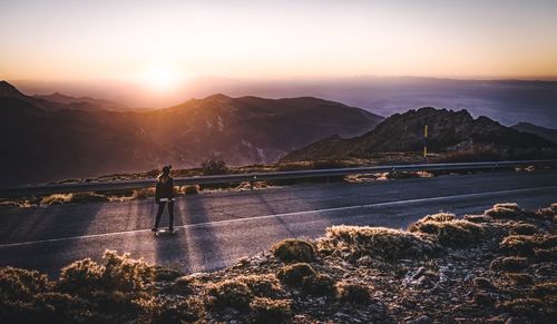 High angle view of woman skateboarding on country road against mountains