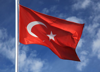 Low angle view of turkish flag waving against sky