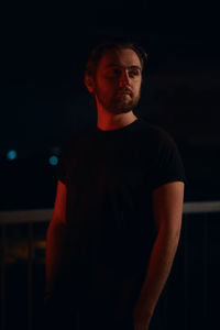 Young man standing against black background