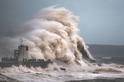 Waves splashing on shore against clear sky