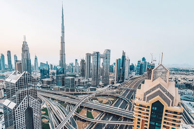 Modern buildings in dubai city with burj khalifa and multilevel road junction against sky