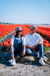 Men sitting on field against clear sky