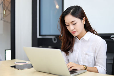 Young businesswoman using laptop at office